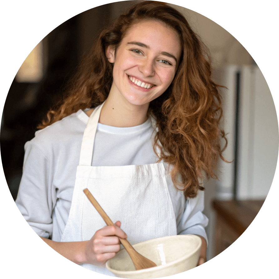 Emma, the chef of Value Recipe, smiling while holding a mixing bowl and wooden spoon in a cozy kitchen.